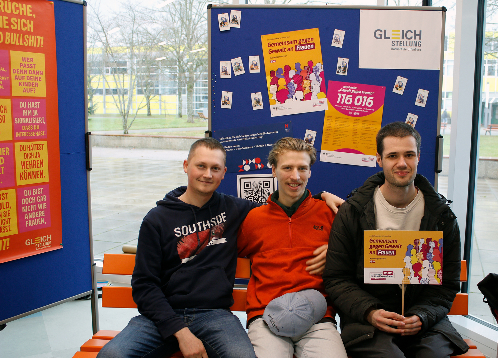 Drei junge Männer sitzen auf der orangenen ank